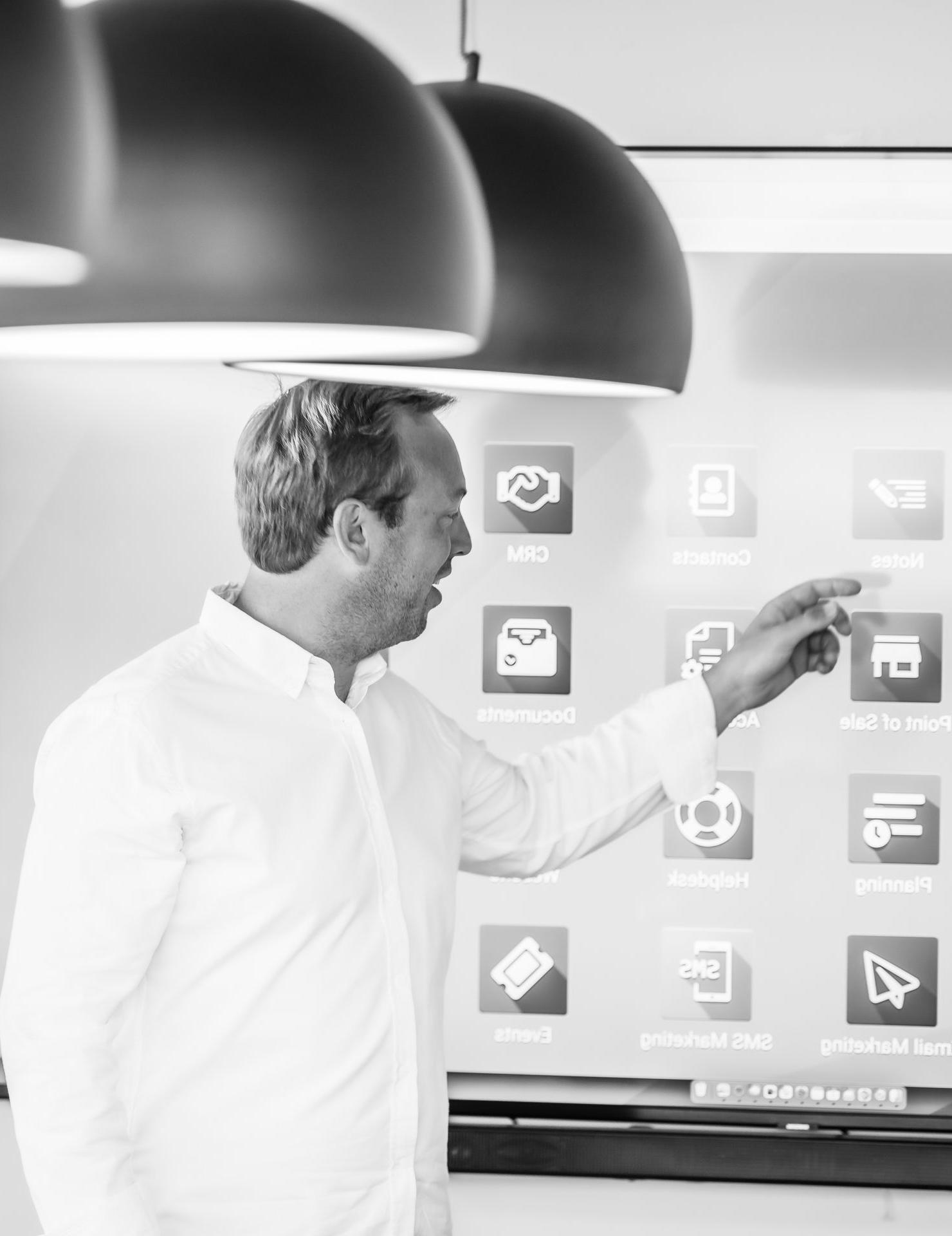 nuestro fundador Arnaud Percy fundador de la empresa de servicios odoo partner muestra aplicaciones odoo en una pantalla en una sala con grandes lámparas