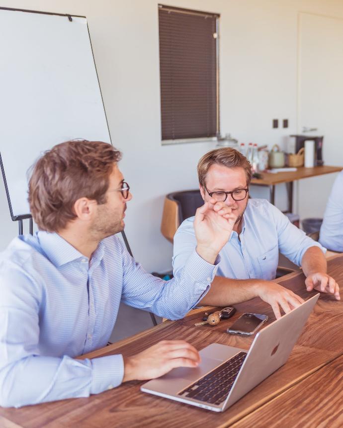 test deux personnes autour d'une table de réunion discutant de ERP et CRM performant pour votre société ? un pc des clés et un téléphone portable se trouve sur cette table