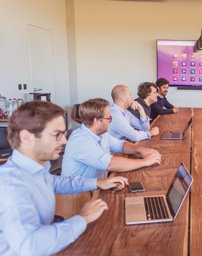 the men from the service company around a table including Valery Jans, Brieuc Thoumsin and Ilias Bitar with their laptop and mobile phone as well as a screen displaying all the Odoo applications, odoo implementation