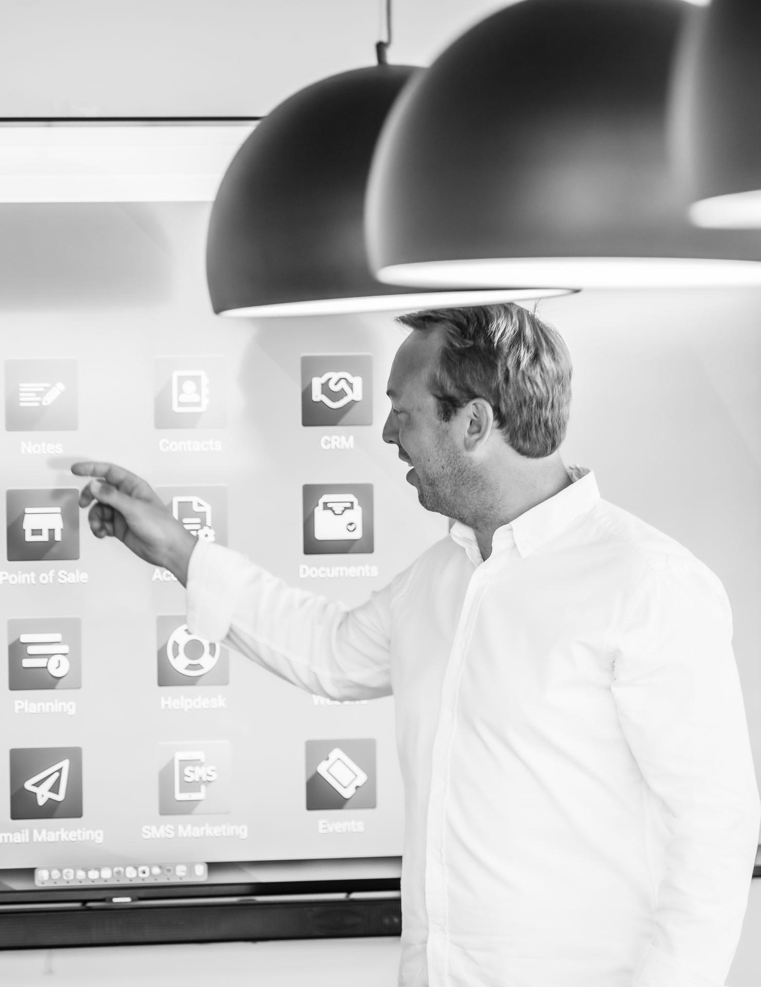 nuestro fundador Arnaud Percy fundador de la empresa de servicios odoo partner muestra aplicaciones odoo en una pantalla en una sala con grandes lámparas